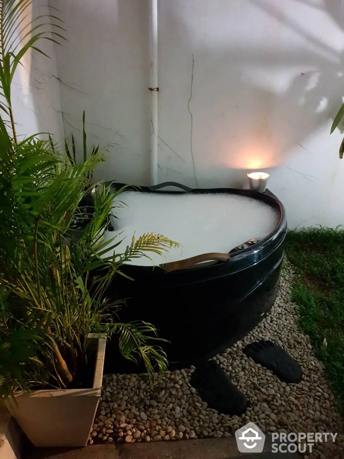 Cozy outdoor hot tub surrounded by lush greenery and ambient lighting, perfect for relaxing evenings in a private backyard oasis.