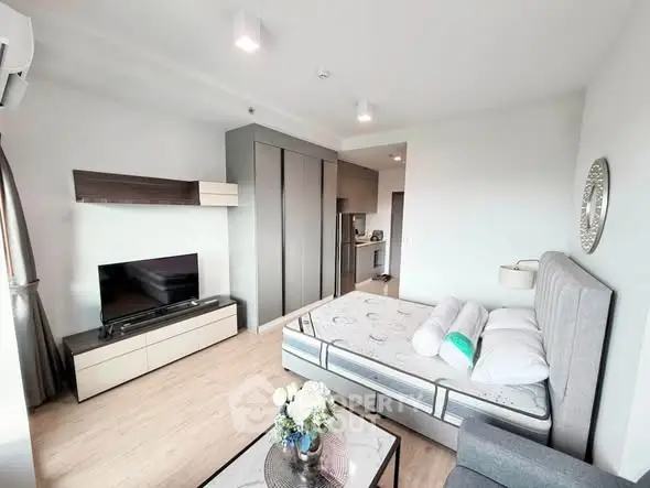Modern studio apartment with stylish decor and open layout, featuring a cozy bed and entertainment area.