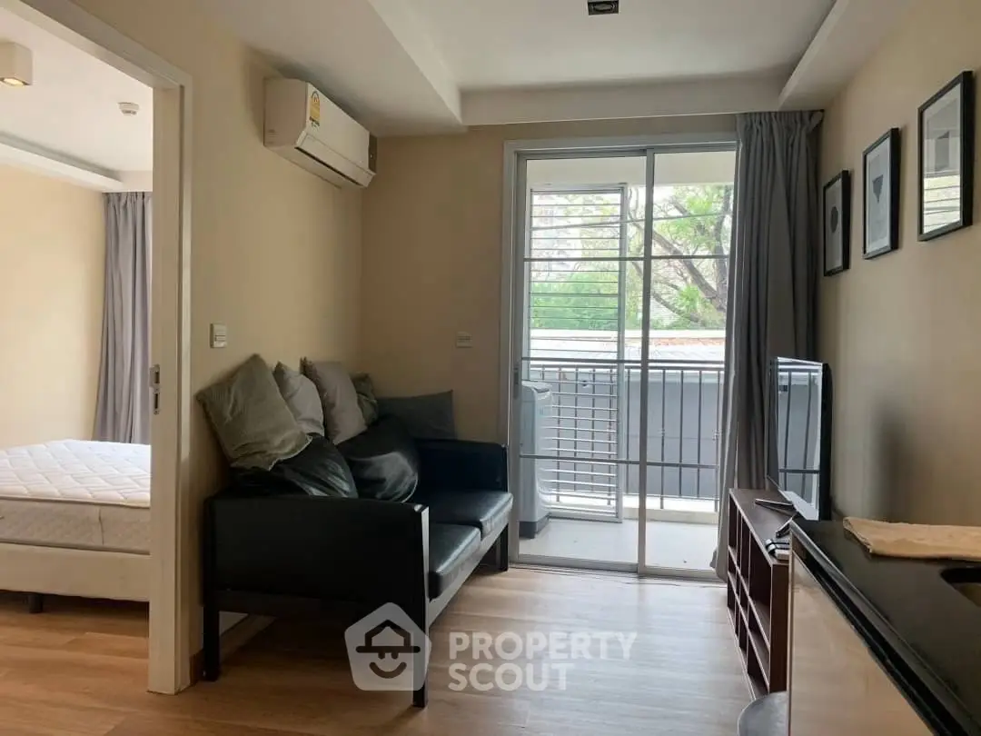 Cozy living room with balcony access in modern apartment, featuring sleek furniture and natural light.