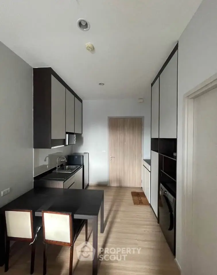 Modern kitchen with sleek cabinetry and dining area in a stylish apartment.
