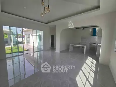 Spacious open-plan living area with modern kitchen and large windows overlooking garden