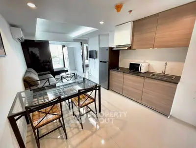 Modern open-layout living room with kitchen, featuring sleek furniture and appliances.