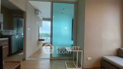 Modern apartment interior with glass partition and wooden flooring, featuring a cozy living area and a compact kitchen.