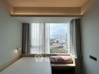 Modern bedroom with large window offering stunning city view and natural light.