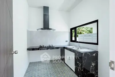 Modern kitchen with sleek black marble countertops and gas stove, featuring a stylish open layout and natural light.