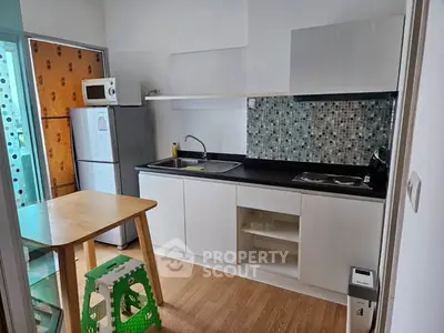 Modern kitchen with sleek cabinets, mosaic backsplash, and compact dining area.