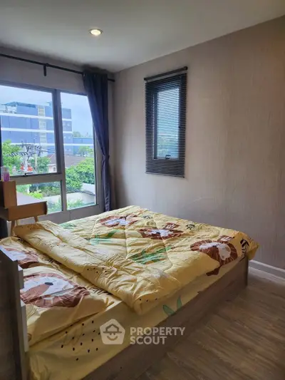 Cozy bedroom with large window and modern decor in urban apartment.