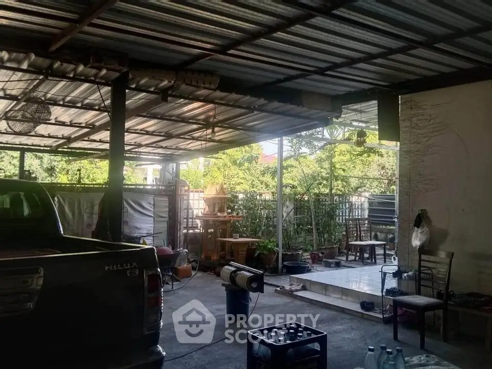 Spacious covered parking area with garden view and seating arrangement.