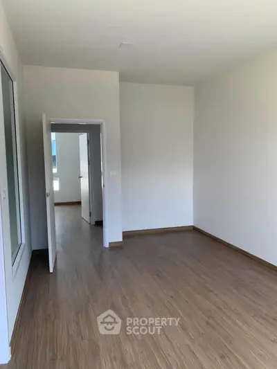 Spacious empty room with wooden flooring and white walls, ready for customization.