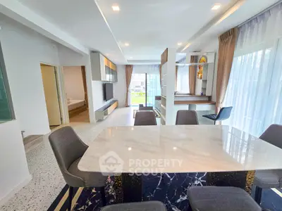 Modern open-plan living and dining area with elegant marble table and large windows.