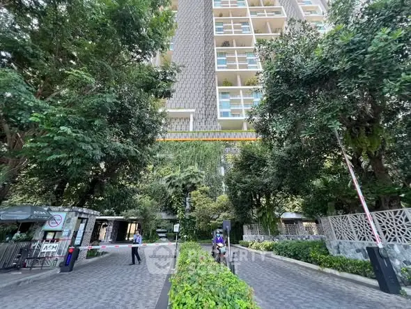 Luxurious high-rise building entrance surrounded by lush greenery and modern design.