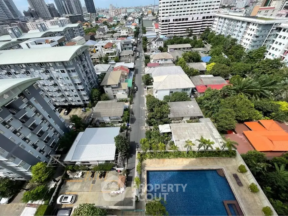 Stunning aerial view of urban neighborhood with pool, showcasing vibrant cityscape and modern residential buildings.