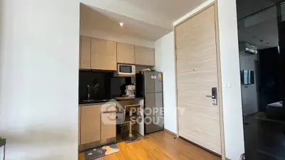 Modern compact kitchen with wooden cabinets and stainless steel appliances in a cozy apartment.