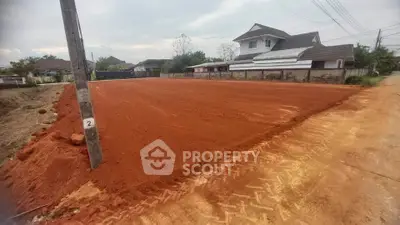 Vacant land plot ready for development in a residential neighborhood with nearby houses.