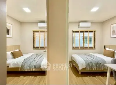 Modern twin bedroom with wooden flooring and stylish decor