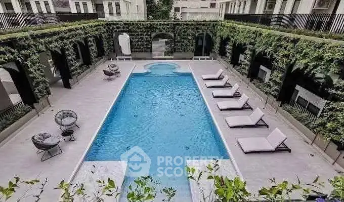 Luxurious residential pool area with elegant lounge chairs and lush greenery.