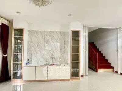 Spacious living area with elegant cabinetry and staircase, perfect for modern living.