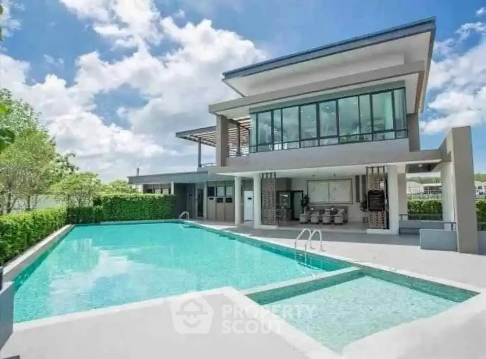 Luxurious modern house with stunning pool and spacious outdoor area under clear blue sky.