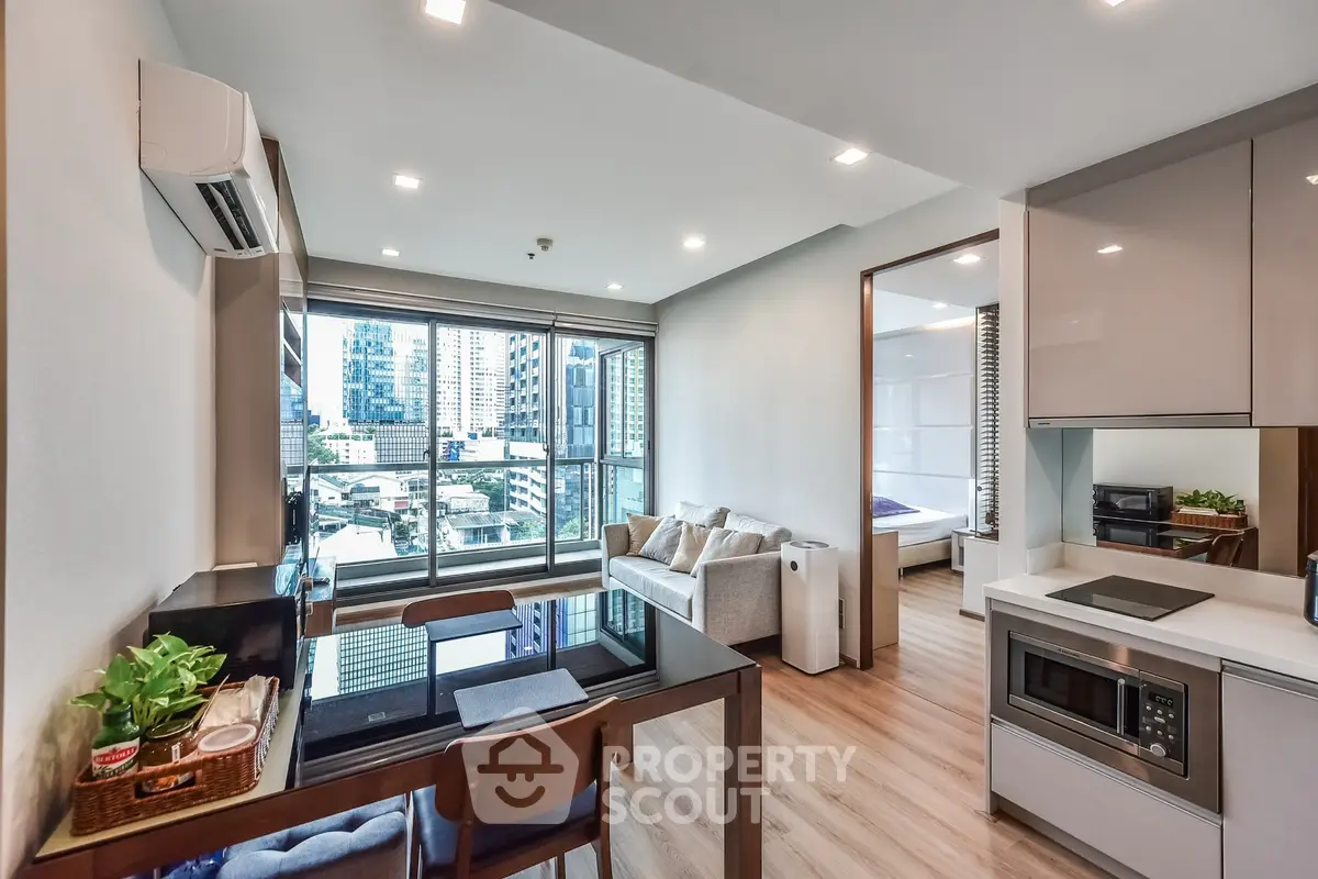 Modern open-plan living room with city view, featuring sleek kitchen and cozy seating area.