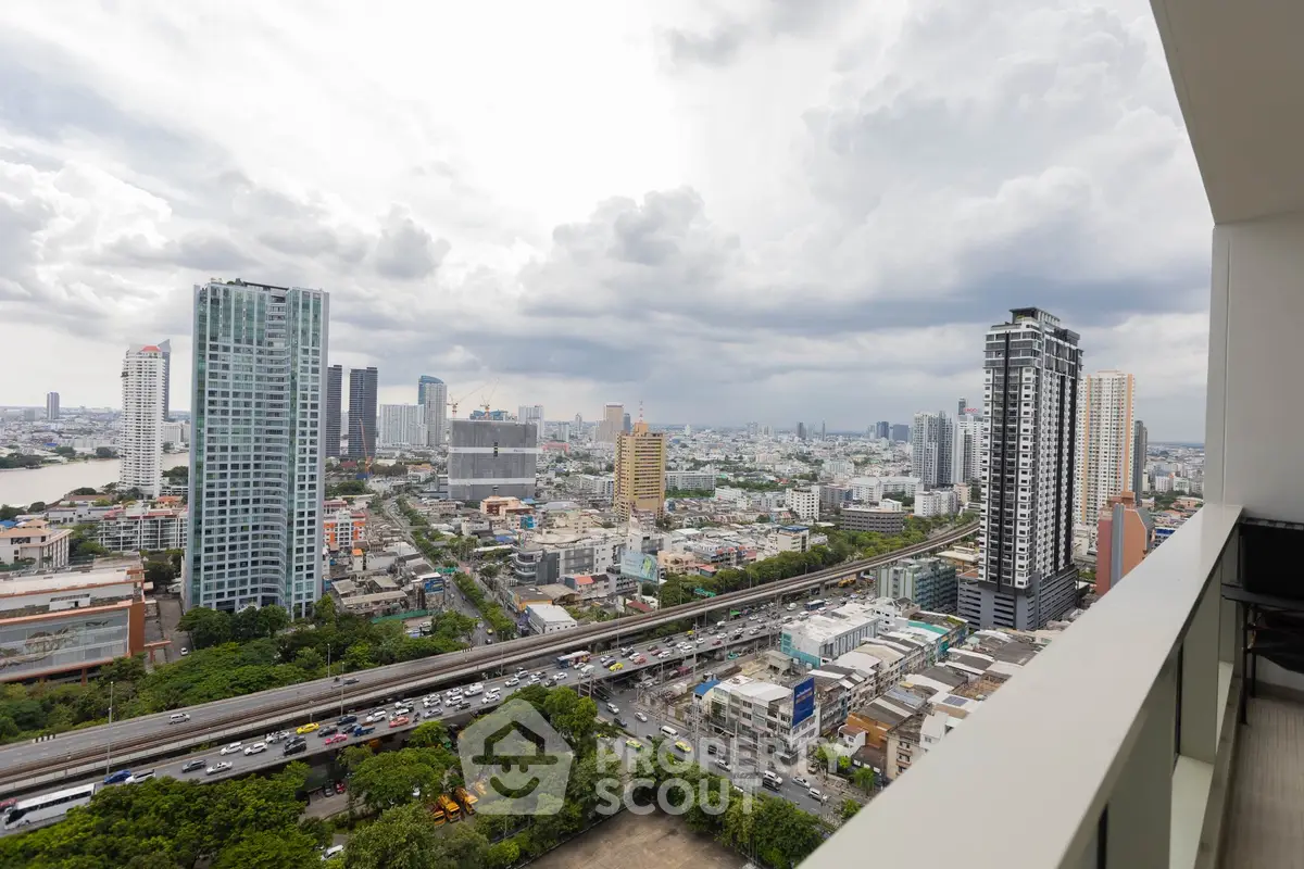 Stunning cityscape view from a high-rise balcony overlooking urban skyline and bustling streets.