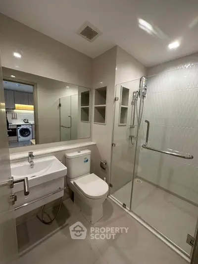 Modern bathroom with glass shower and sleek fixtures in contemporary apartment.