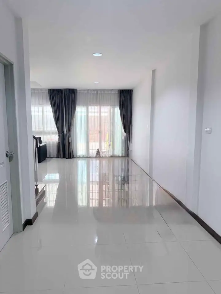 Spacious modern living room with glossy tile flooring and large windows for natural light.