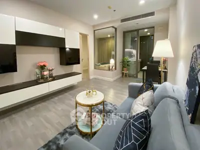 Elegant living room with modern furnishings, sleek entertainment unit, and tasteful decor leading to a cozy balcony.