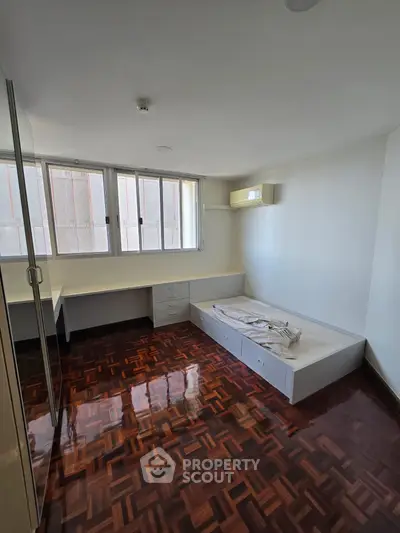 Spacious bedroom with wooden flooring and built-in storage in modern apartment.