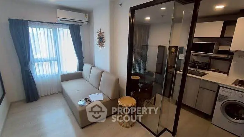 Modern apartment with cozy living room and sleek kitchen featuring washing machine and microwave.