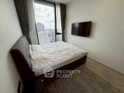Modern bedroom with city view and wall-mounted TV in high-rise apartment.