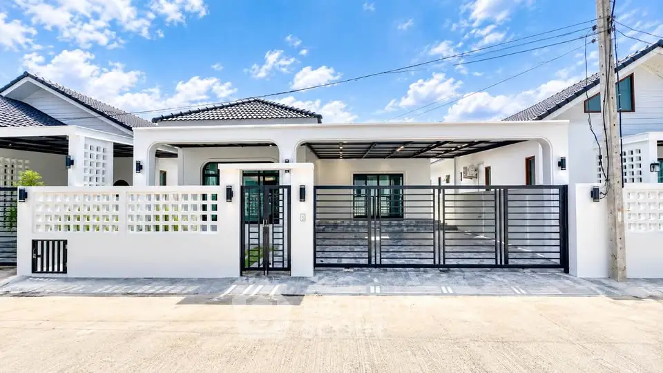 Modern single-story house with gated entrance and stylish facade under a clear blue sky.