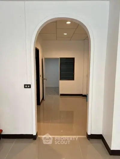 Modern interior with archway and tiled flooring, showcasing minimalist design.