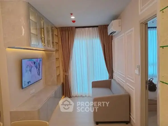 Modern living room with elegant decor and natural light, featuring a cozy sofa and wall-mounted TV.