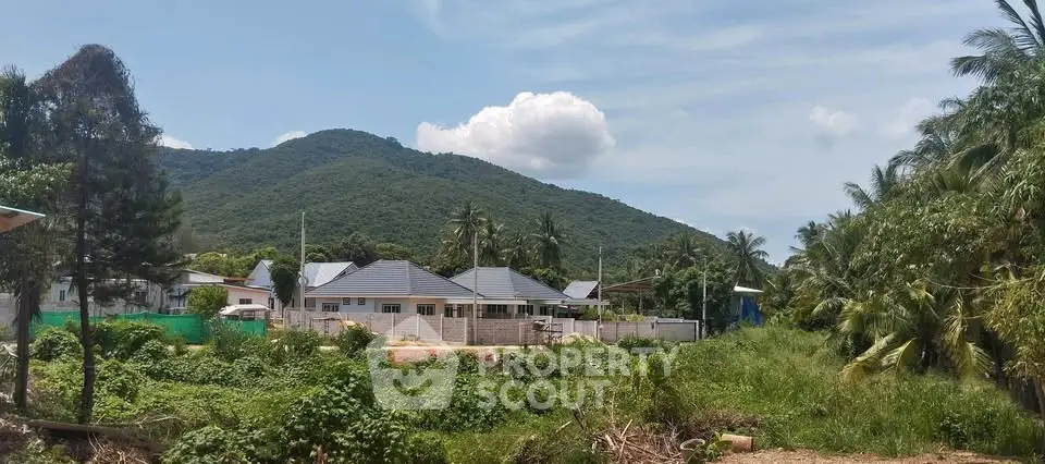 Scenic view of a residential property with lush greenery and mountain backdrop, ideal for nature lovers.