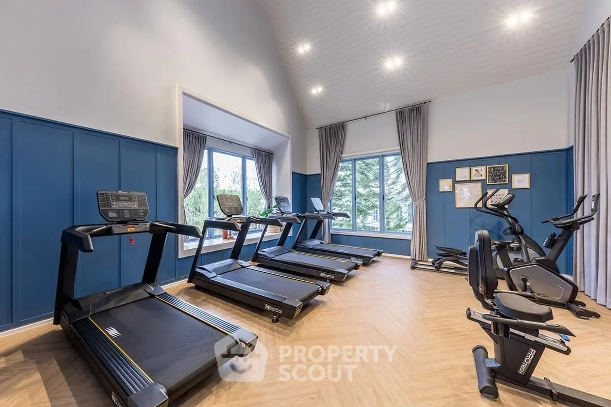 Spacious home gym with modern equipment and large windows for natural light.