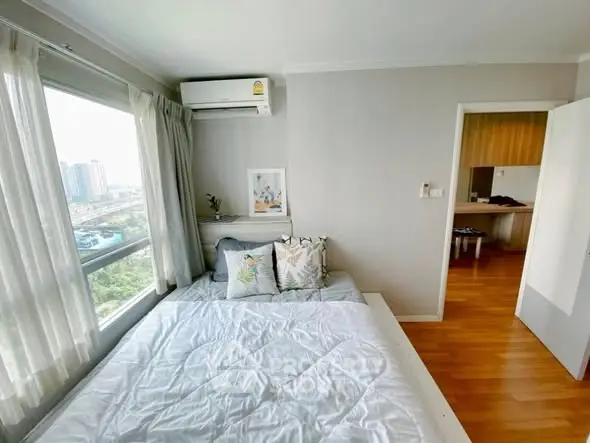 Bright bedroom with large window and modern decor in a high-rise apartment.