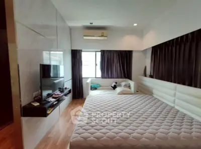 Spacious bedroom with modern decor and large windows for natural light.