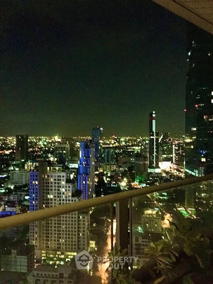 Stunning cityscape view from a high-rise balcony at night, showcasing vibrant urban lights.
