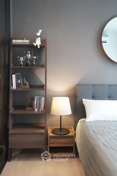 Cozy bedroom with stylish decor, featuring a wooden shelf, modern lamp, and elegant bedding.