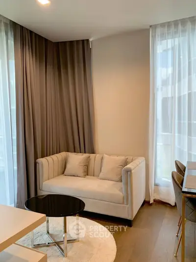 Cozy living room with elegant sofa and modern decor, featuring floor-to-ceiling windows and stylish curtains.