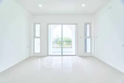 Spacious and bright living room with large windows and balcony access, offering a serene view.