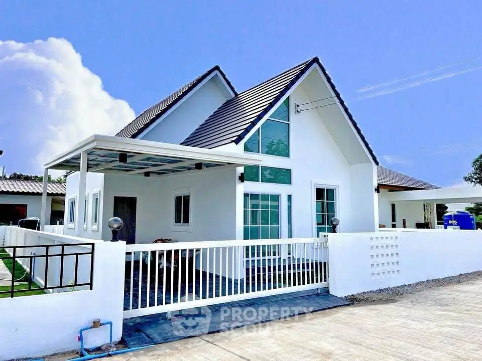 Charming modern white house with pitched roof and spacious front yard in a serene neighborhood.