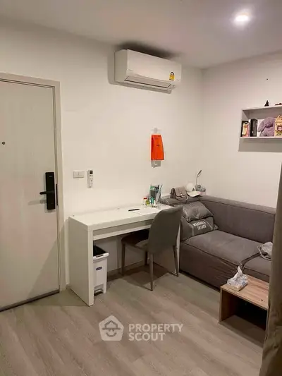 Cozy living room with modern decor, featuring a comfortable sofa, study desk, and air conditioning unit.