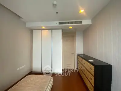 Spacious bedroom with modern wardrobe and wooden flooring in a stylish apartment.