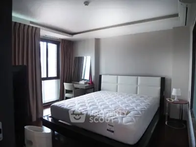 Spacious bedroom with modern furniture and large window for natural light.