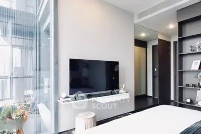 Modern bedroom with sleek TV setup and stylish decor in a high-rise apartment.