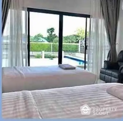 Spacious bedroom with pool view and large windows for natural light