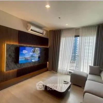 Modern living room with sleek design and large TV, featuring a cozy sectional sofa and elegant lighting.