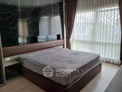 Modern bedroom with large window and stylish decor in a luxury apartment.