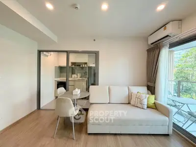 Modern living room with cozy sofa and open kitchen layout, featuring a balcony with a view.